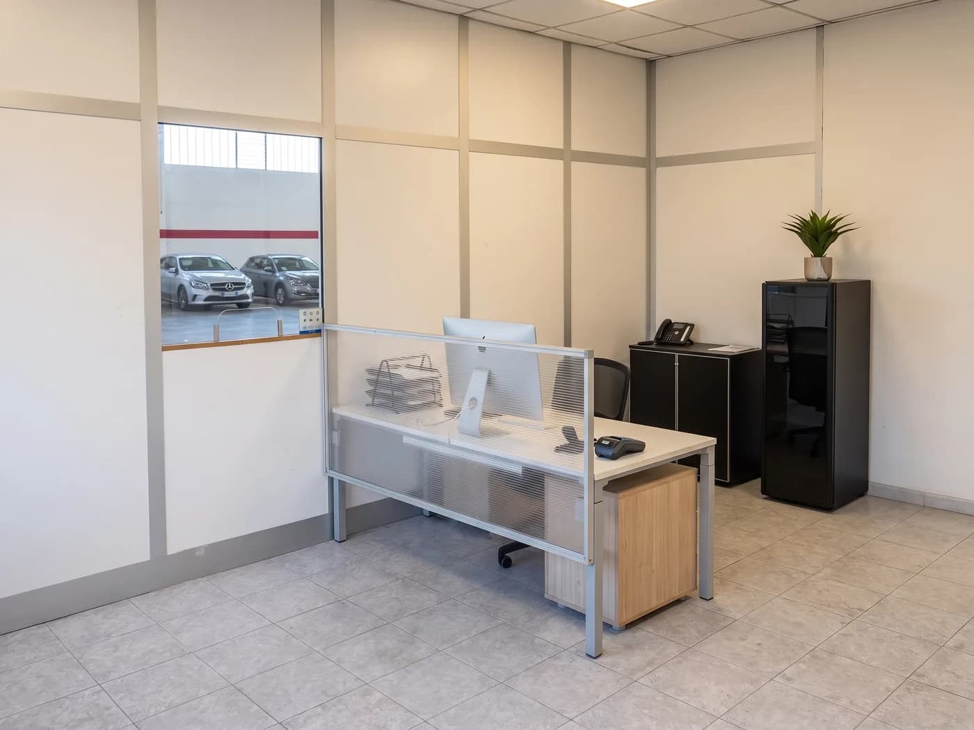 Postazione check-in dell'ufficio accettazione di EuroParking Malpensa con finestra sul capannone